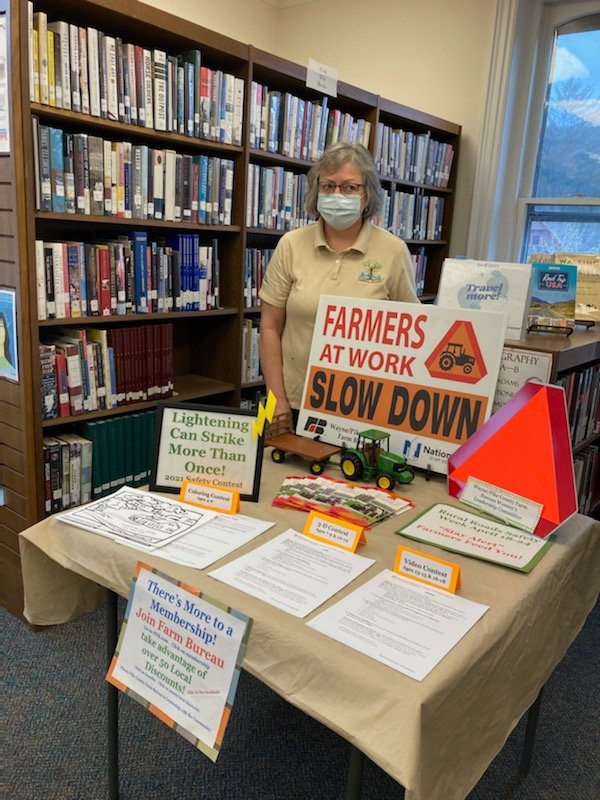 Women's Leadership Chair Bonnie LaTourette with a “Rural Roads Safety” display in the Wayne County Public Library. Drivers should be cautious when they see a "Farmers at Work" sign or a slow-moving vehicle emblem.
